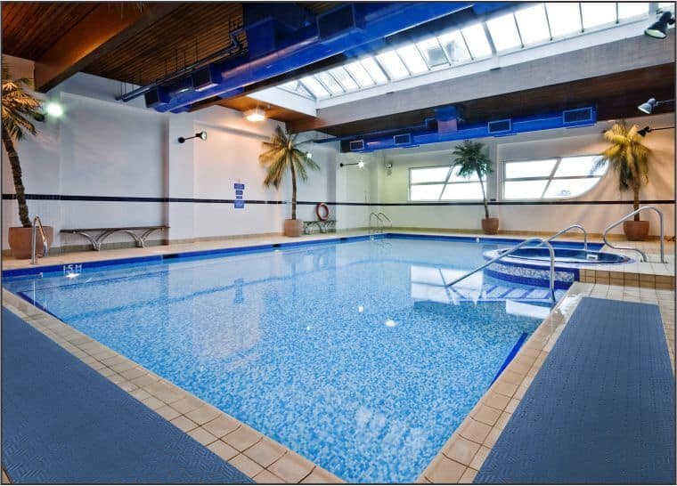 An indoor swimming pool with a Wet Step Floor Mat in a large building.