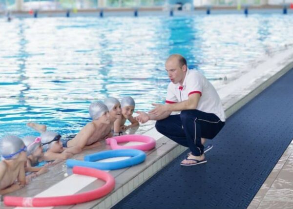 A group of people enjoying a refreshing swim on the Wet Step Floor Mat in a swimming pool.